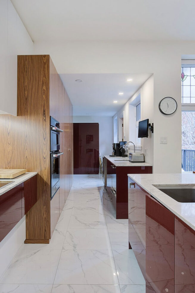 Cuisine avec des accents rouge vin et des grand armoires blanc avec du bois à quelques endroits.