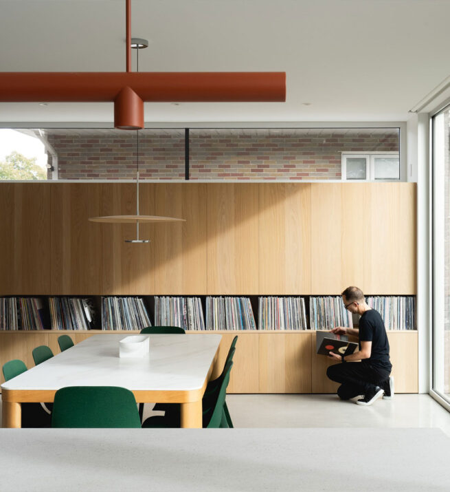 De grandes fenêtres avec une table et une bibliothèque qui occupe tout le mur.