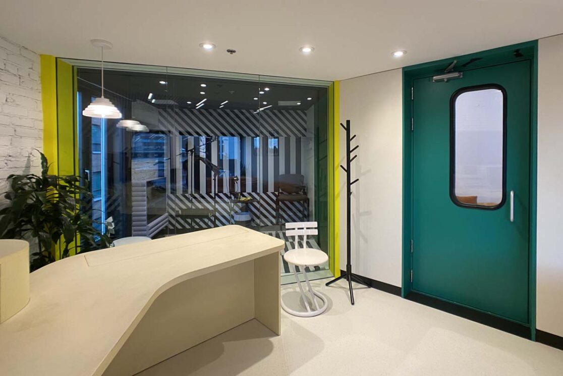 Porte turquoise avec une grande fenêtre pour enregistrer avec des accents jaune.