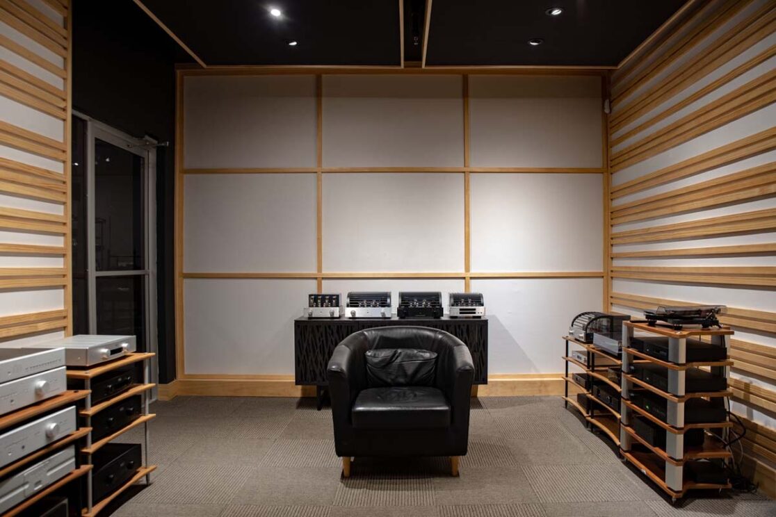 Une salle avec des vieux équipements audios avec un fauteuil.