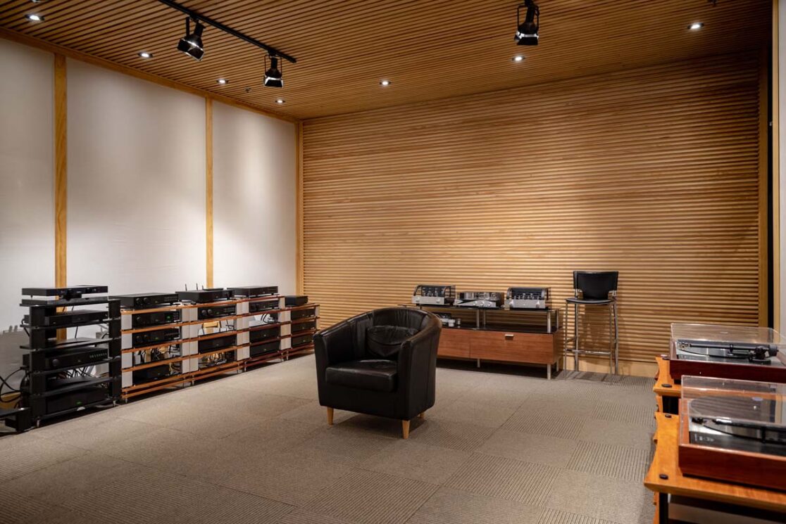 Une salle avec des vieux équipements audios avec un fauteuil.