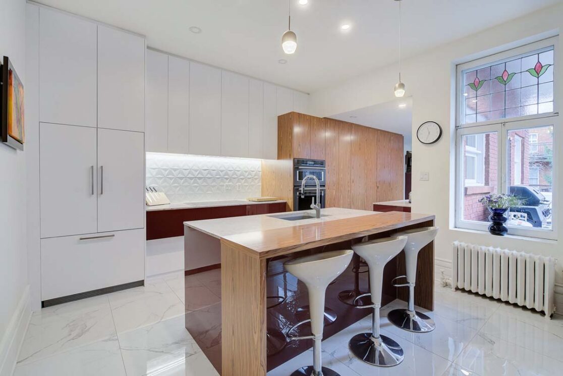 Cuisine avec des accents rouge vin et des grand armoires blanc avec du bois à quelques endroits.