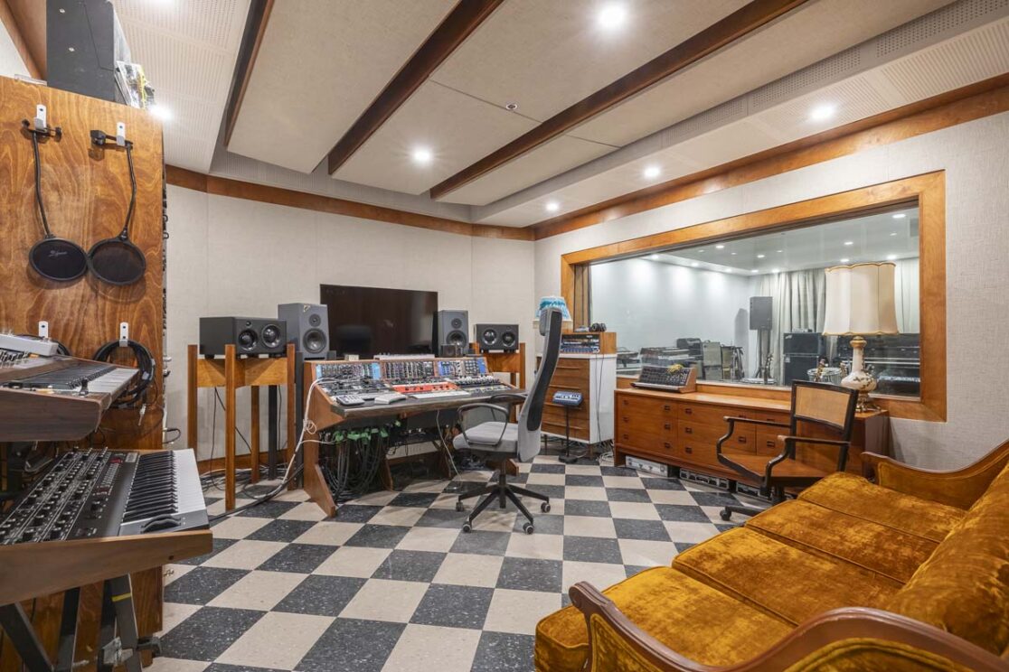 Studio d'enregistrement retro avec des pianos et un ordinateur pour enregistrer.