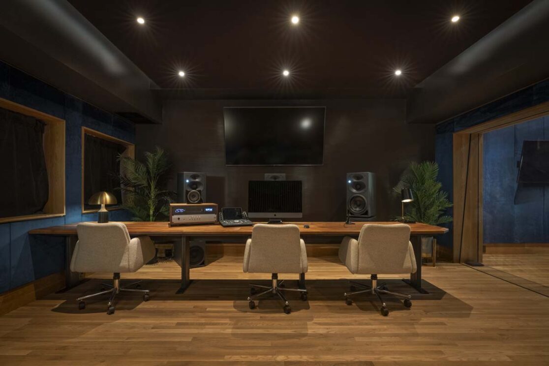 un studio avec un grand bureau avec des murs en velours bleu avec des speakers et un télévision.