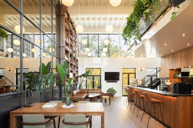 Un bureau spacieux avec une grande bibliothèque, des tables de travail et un grand canapé.