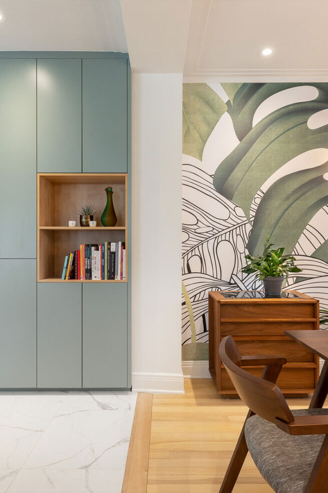 Cuisine et salle à manger avec des armoires turquoise et un joli mur coloré avec des feuillages.