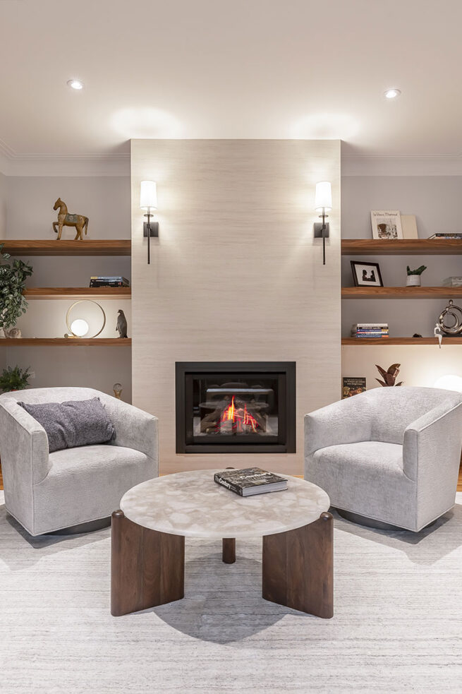 Salon confortable avec une cheminée, deux bibliothèques de chaque côté, deux canapés et une table.