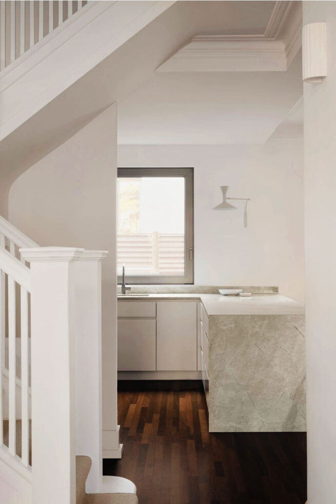 Escaliers blanche avec vue sur la cuisine.