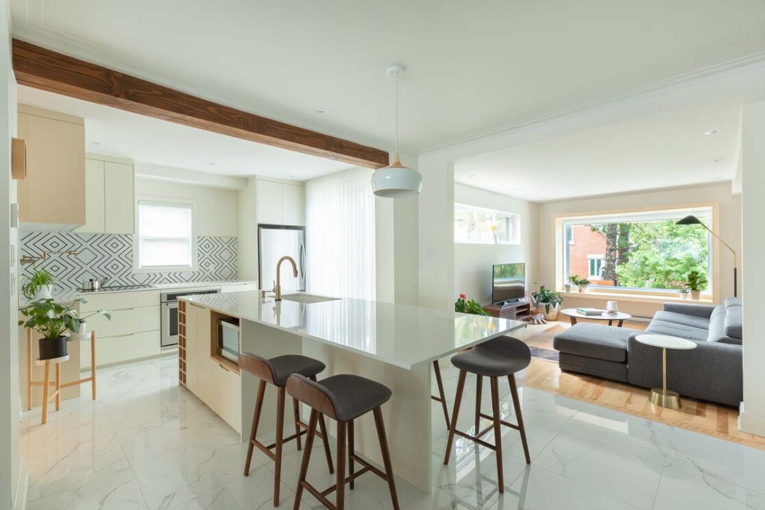 Cuisine avec un grand ilot central blanc avec vue sur le salon.