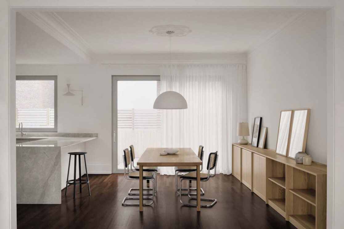 Salle à manger avec des meubles en bois et une grande porte coulissante menant à la court arrière.
