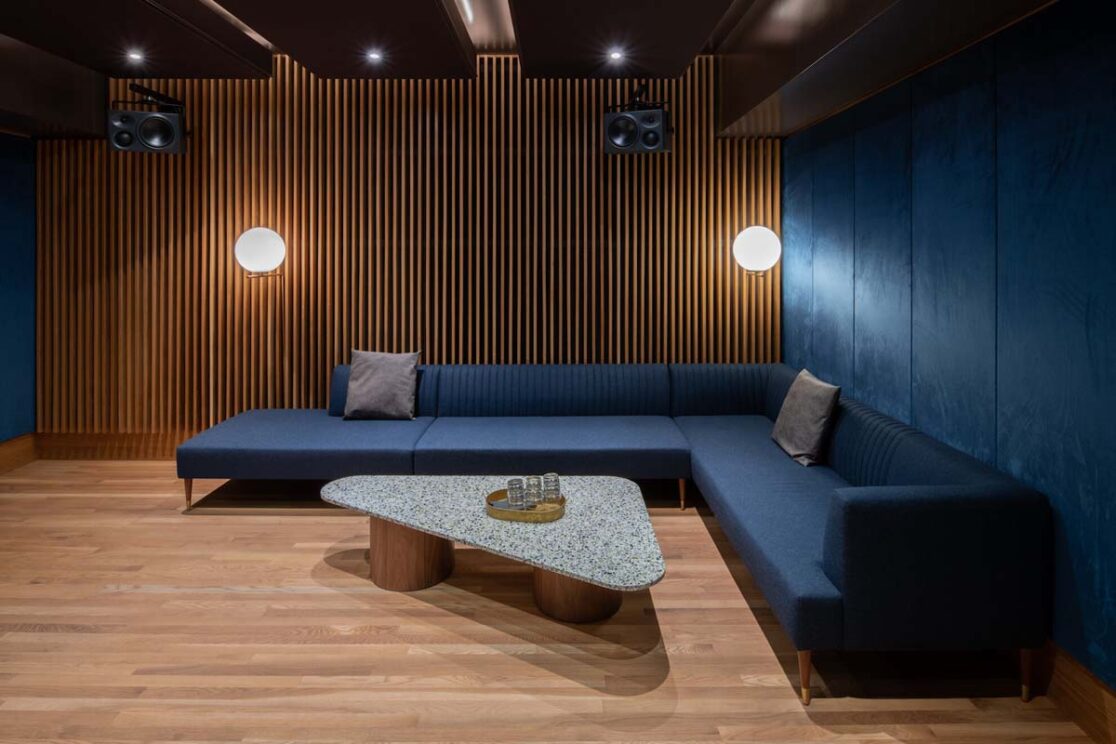 Un studio comprenant un canapé bleu, un mur accentué en velours bleu.