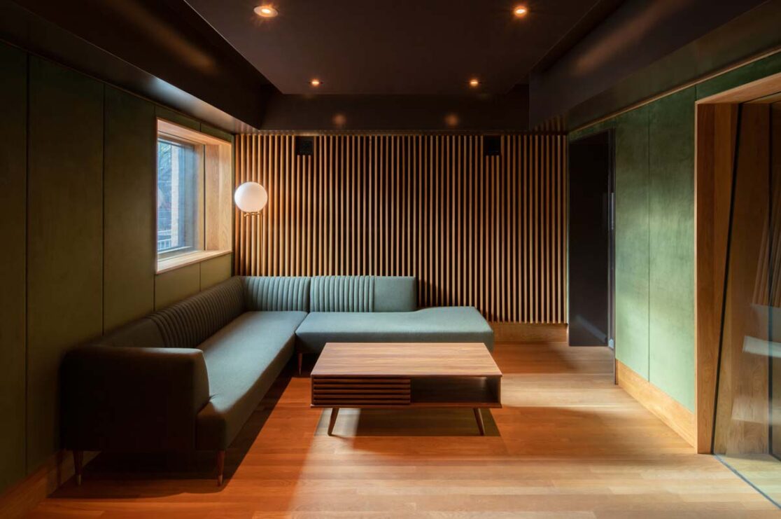 Studio d'enregistrement avec un canapé vert et un murs accents en velours vert.