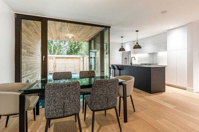 Une salle à manger dotée de larges fenêtres offrant une vue sur la cour arrière.